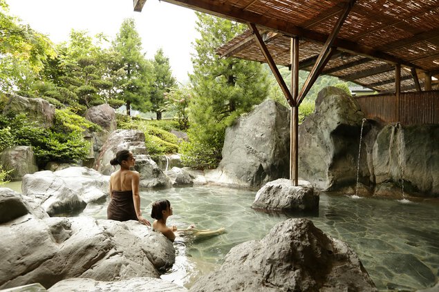 日本庭園とその先の山々を望む大露天風呂
